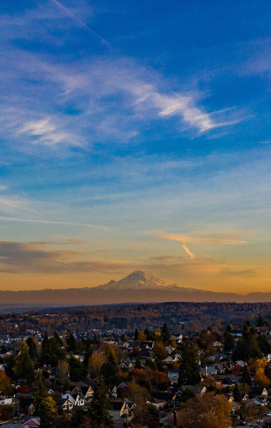 A cityscape with a mountain in the background during sunset.
