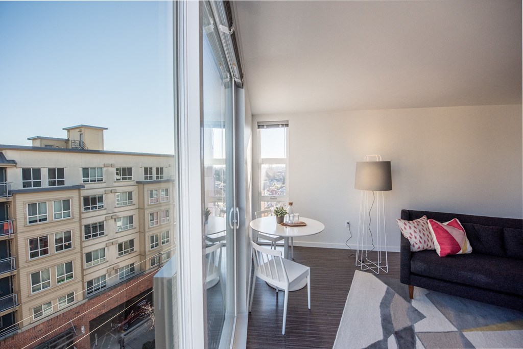 a bedroom with a large window and a balcony with a table and chairs