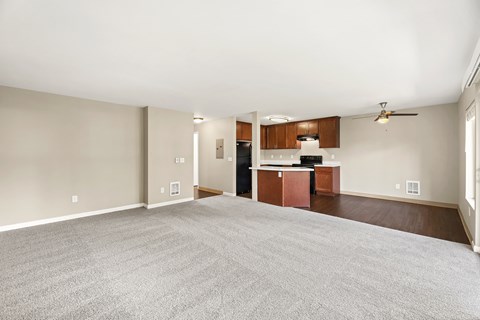 A spacious living room with a kitchenette in the background.