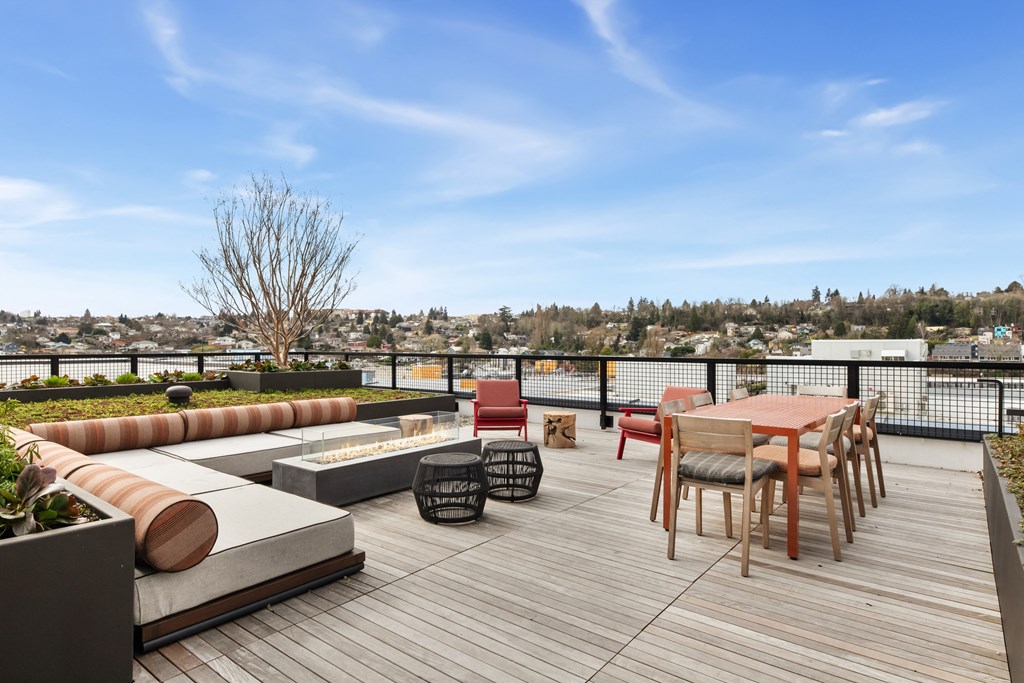 A wooden deck with a table and chairs overlooking a cityscape.