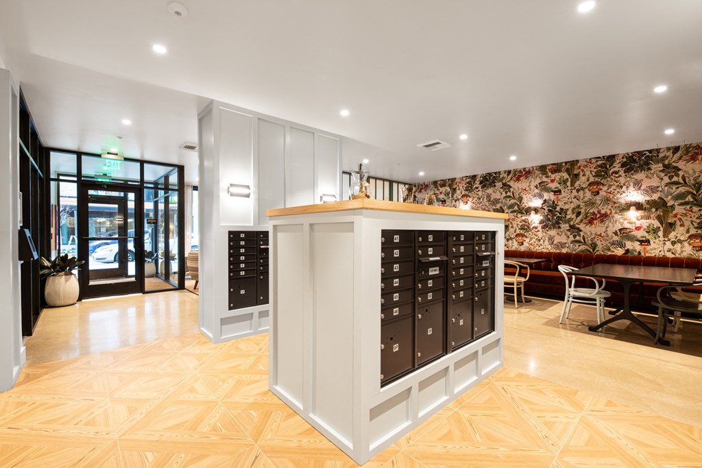 A white reception desk with black drawers is in the middle of a room with wooden flooring.