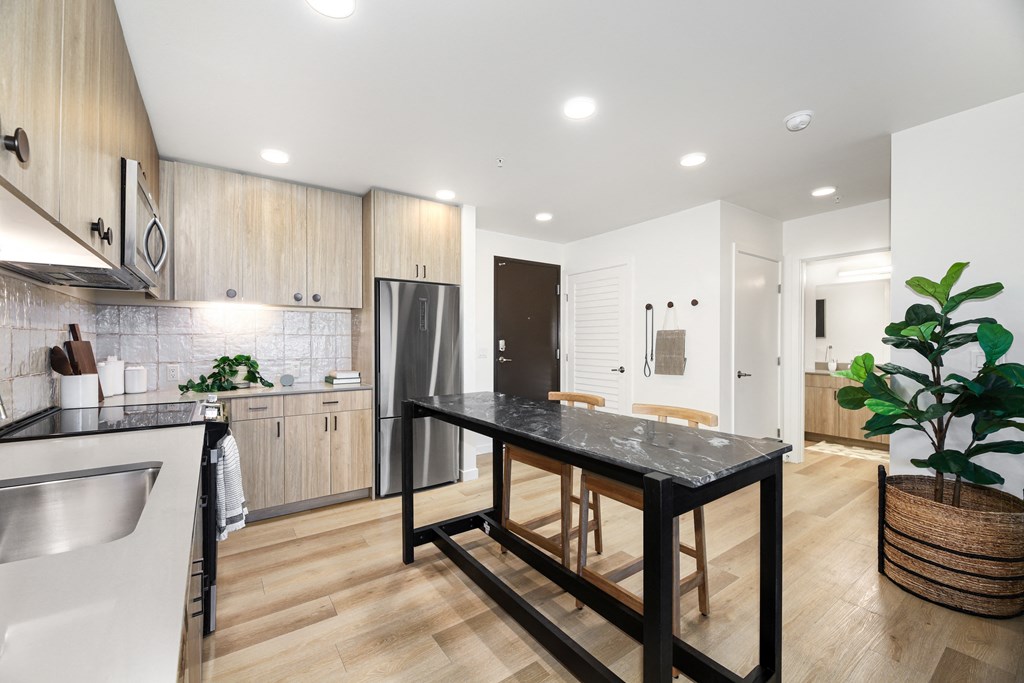 A modern kitchen with a black island and wooden cabinets.