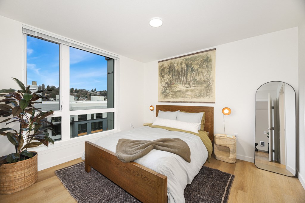 A bedroom with a large bed and a view of the outdoors through the window.