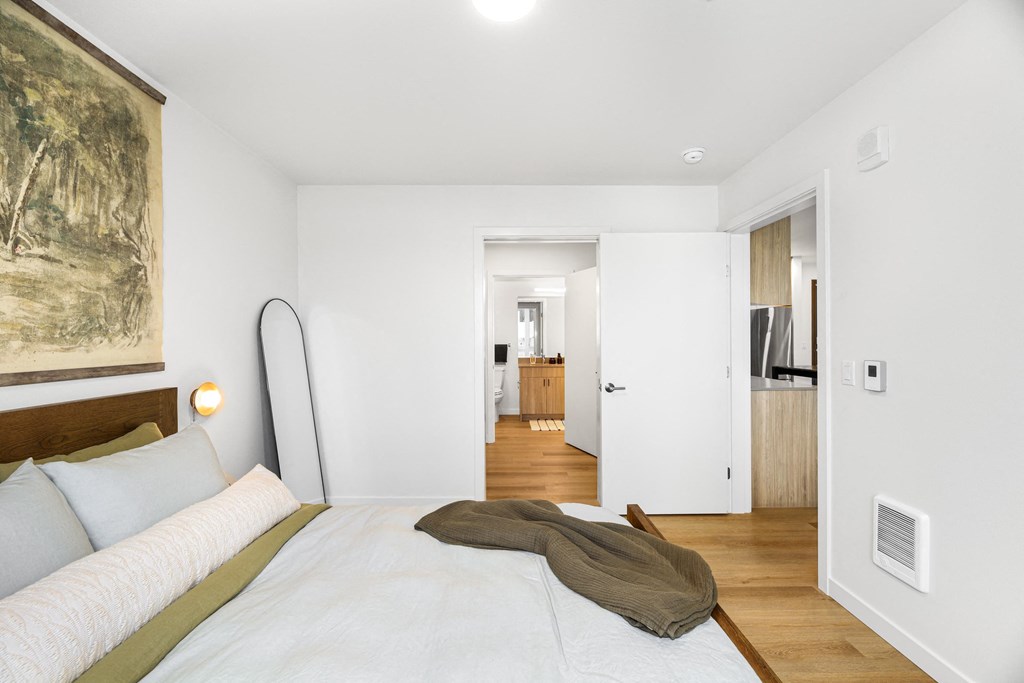 A bedroom with a large bed and a painting on the wall.