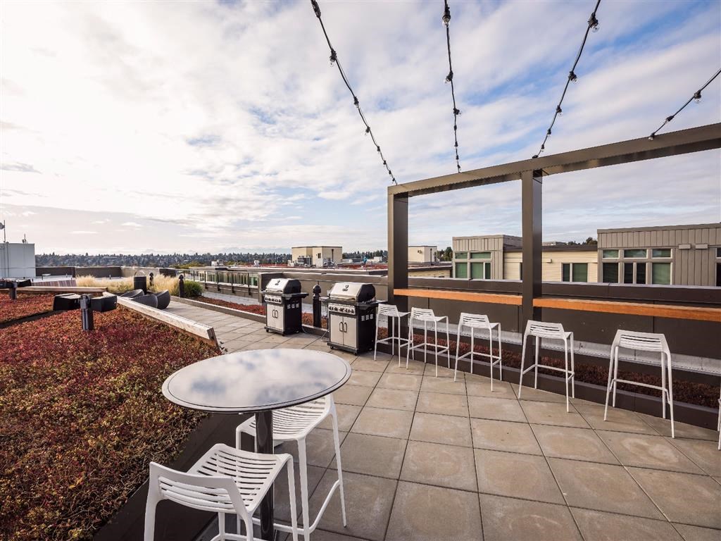 a rooftop patio with tables and chairs and a view of the city