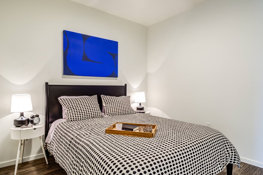 a bedroom with a bed and a blue painting on the wall