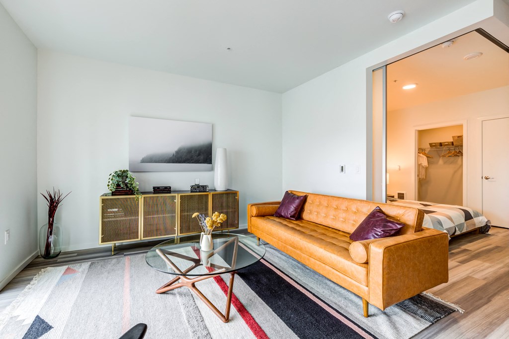 a living room with a yellow couch and a glass coffee table