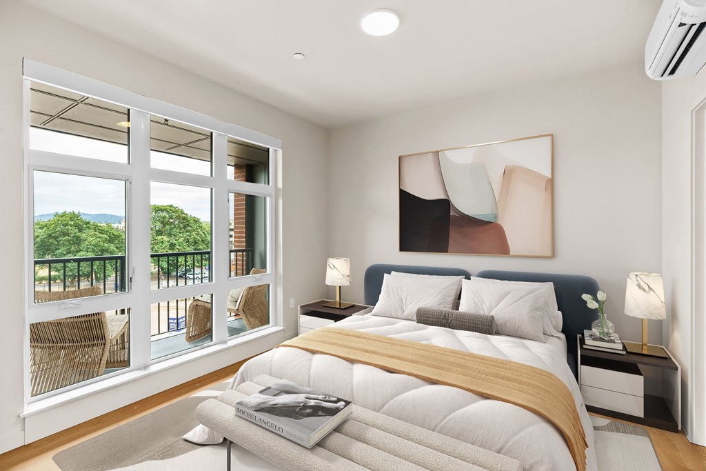 A bedroom with a large bed and a view of the outdoors through the windows.