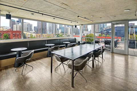 A conference room with a long table and chairs with a view of the city outside the window.