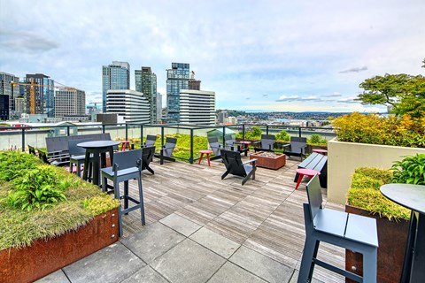 A patio with chairs and tables overlooking a city skyline.