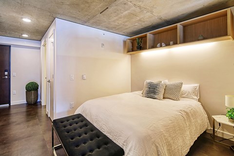 A bedroom with a large bed and a black ottoman.
