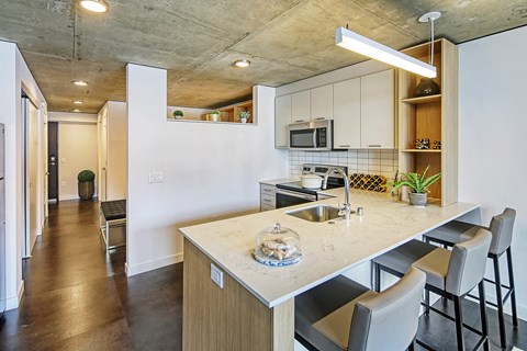A kitchen with a marble countertop and bar stools.