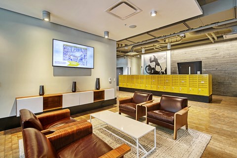 A modern living room with a white sofa, brown leather chairs, and a TV mounted on the wall.