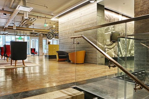 A modern office space with a glass staircase and wooden floors.