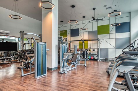 A gym with a variety of equipment including treadmills, weights, and exercise machines.