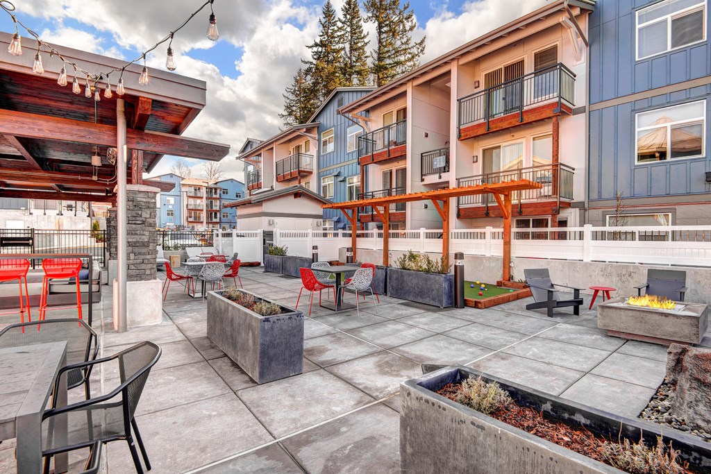 a patio with tables and chairs and buildings in the background