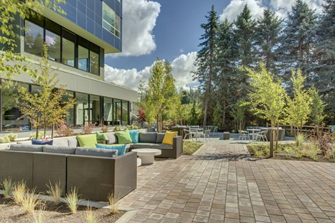 a patio with couches and tables in front of a building