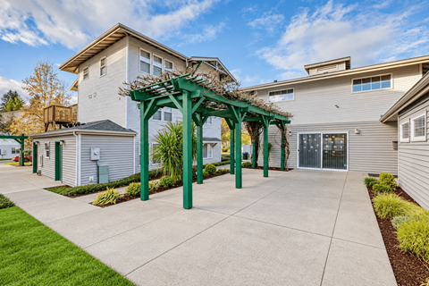 A house with a green pergola in front of it.