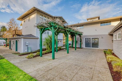A residential area with a green pergola and a concrete walkway.