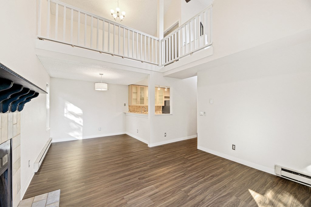 the living room and kitchen of a new home with white walls and wood flooring
