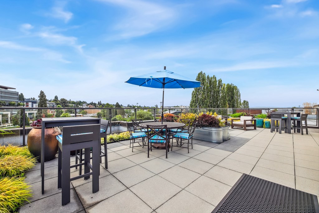 the rooftop patio of a building with tables and chairs and an umbrella