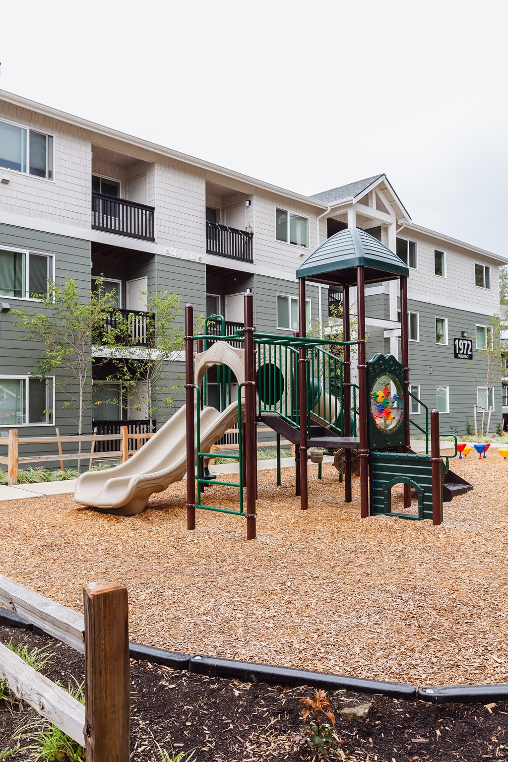a playground with a slide in front of an apartment building