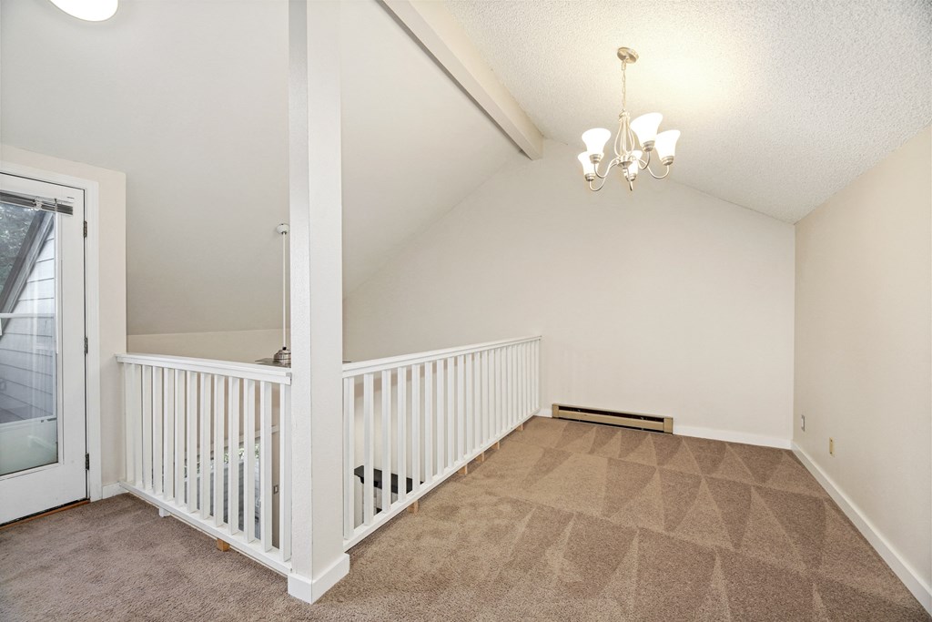 the upstairs landing of a house with a white railing and a door