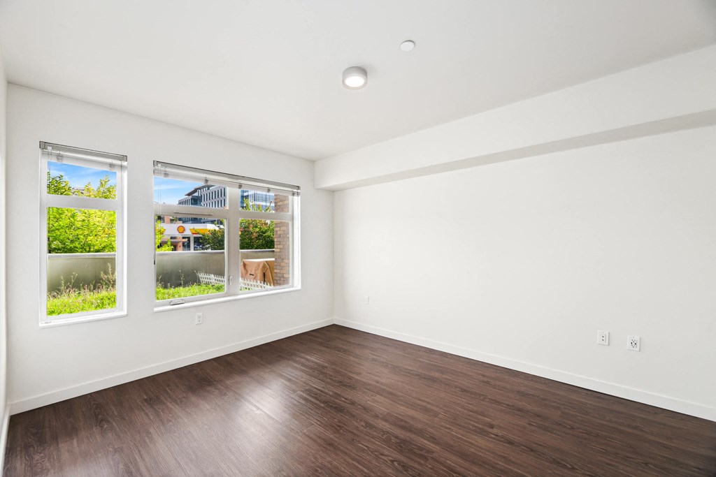a living room with wood floors and white walls and windows