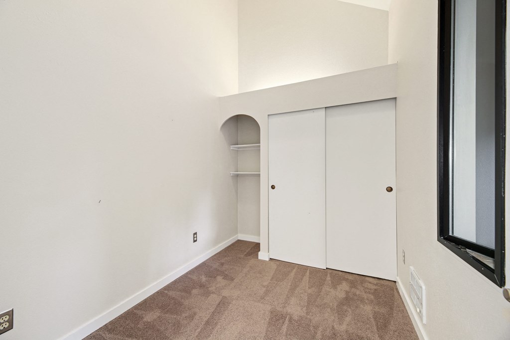 a bedroom with white walls and a closet with white doors