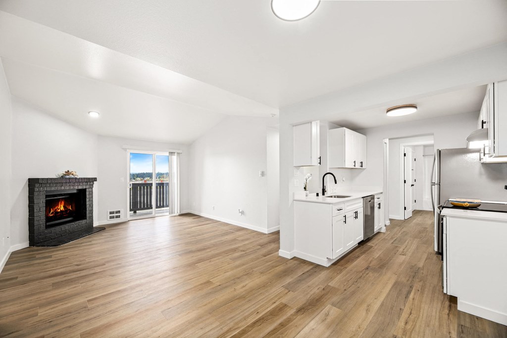 a living room with a fireplace and a kitchen with white cabinets