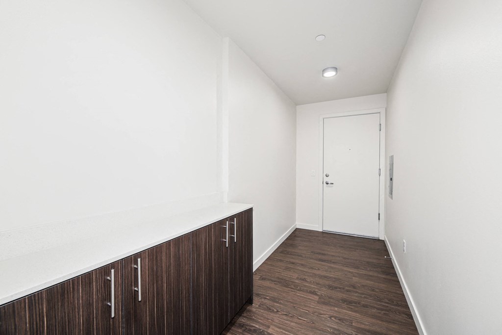 a corridor with white walls and wood floors and a white door