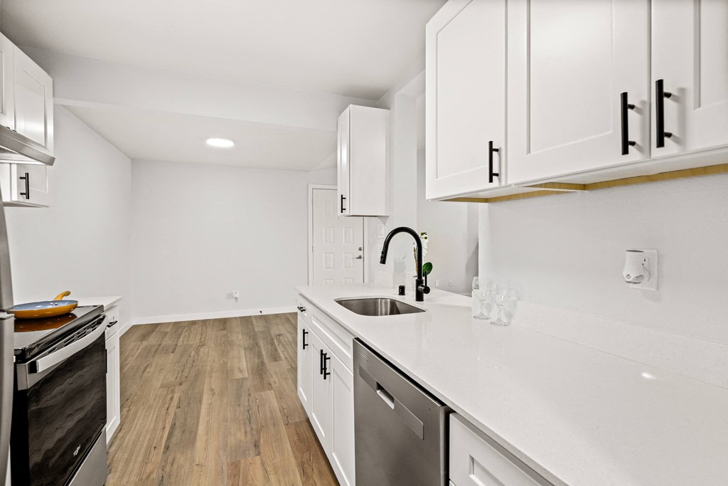 a renovated kitchen with white cabinets and white counter tops and a sink