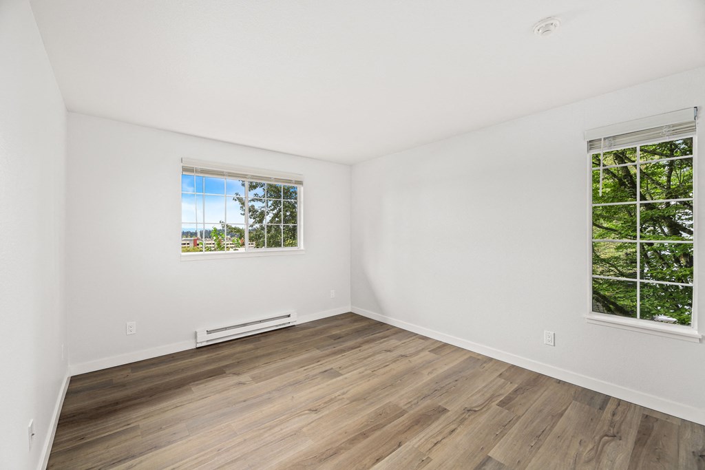 an empty room with white walls and wood floors and a window