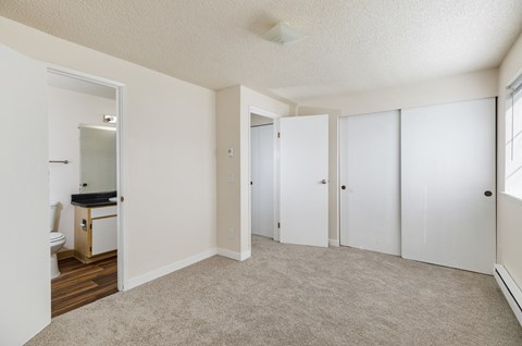 A bedroom with a white door and a carpeted floor.