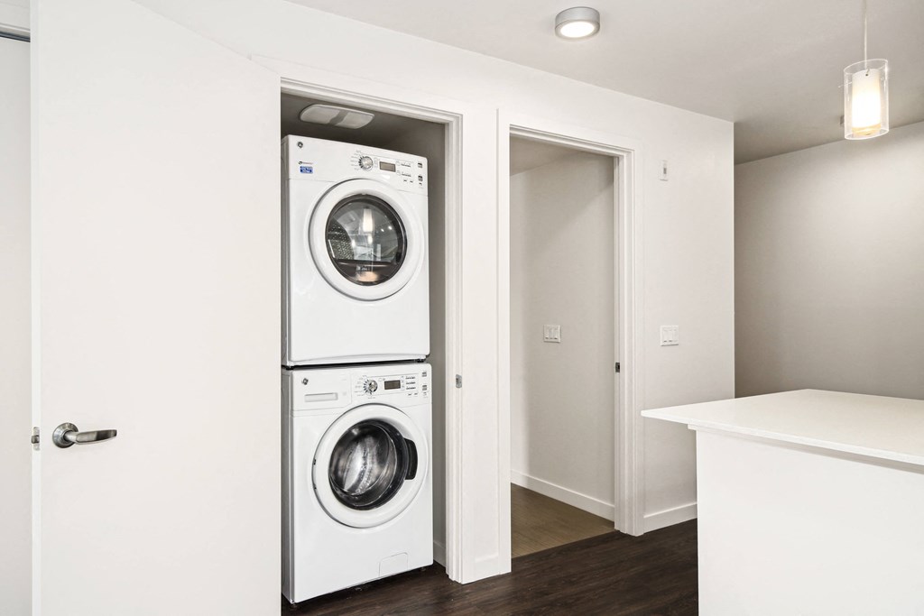 a white washer and dryer in a white laundry room with a door open