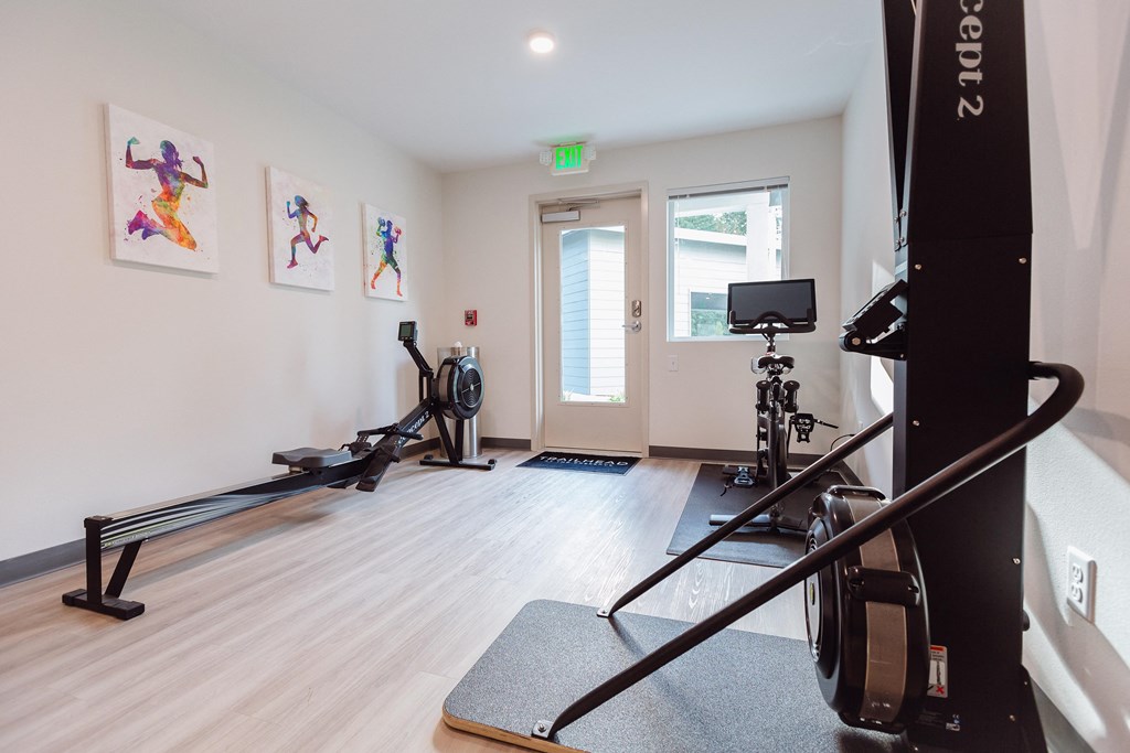 a home gym with exercise equipment and paintings on the wall