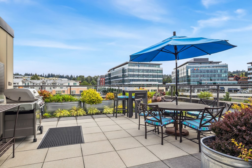 a patio with tables and chairs and an umbrella on a rooftop