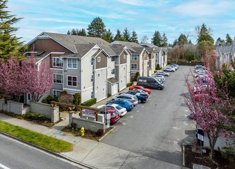 A parking lot with cars and apartment buildings in the background.
