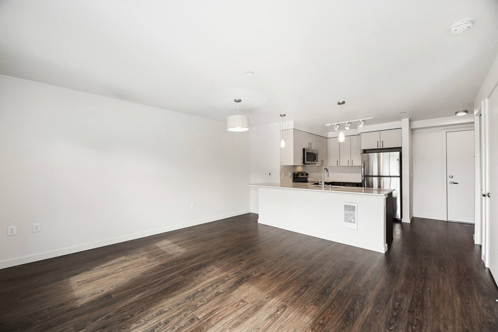 a living room and kitchen with wood floors and white walls