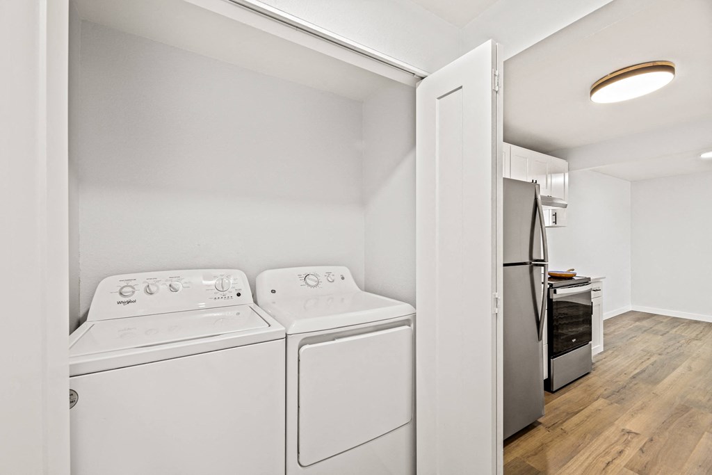a white washer and dryer in a room with a door to a kitchen