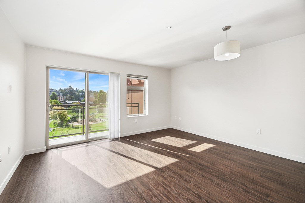 an empty living room with wood floors and a sliding glass door