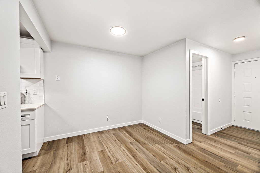 the living room and kitchen of a new home with white walls and wood flooring