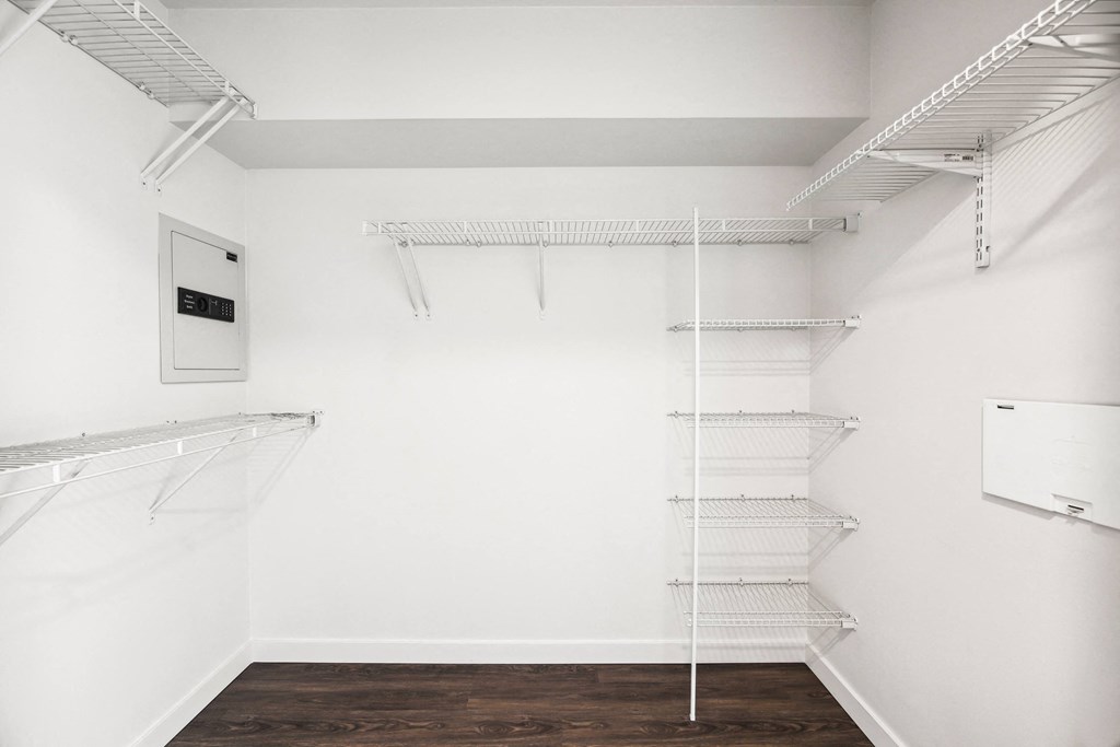 a walk in closet with white walls and white shelves and a white walled closet