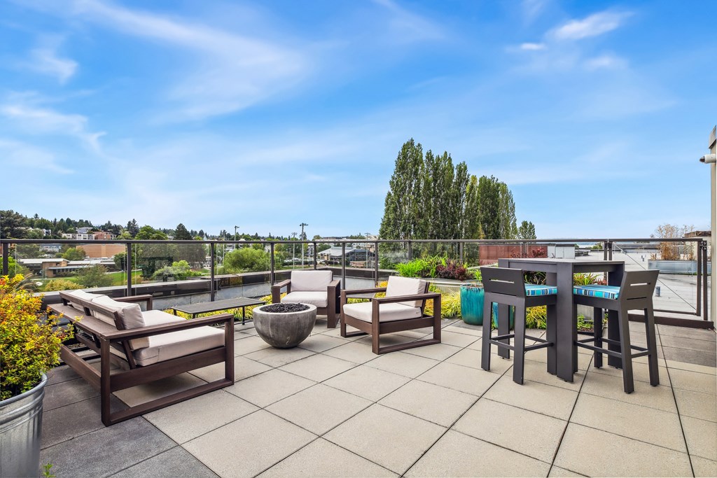 a rooftop patio with chairs and tables and a view of the city