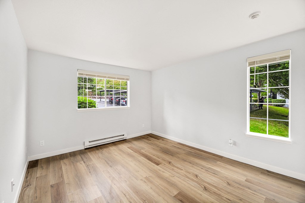 a living room with white walls and wood floors and a window