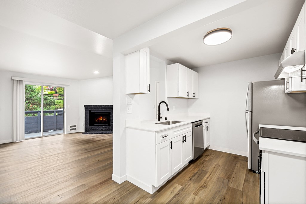 a renovated kitchen with white cabinets and a fireplace
