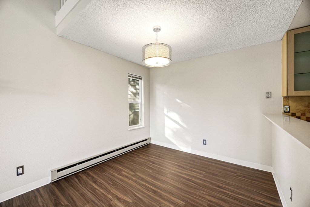 the living room and dining room of an empty house with wood flooring