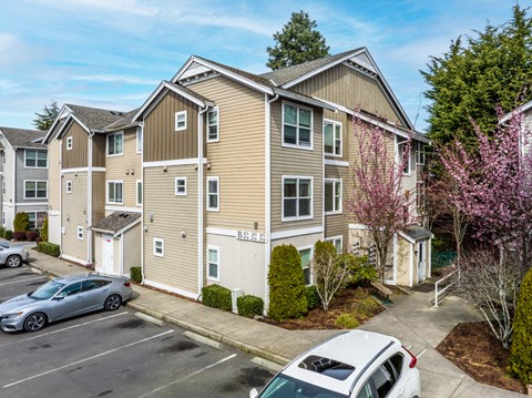 A residential building with a parking lot in front.