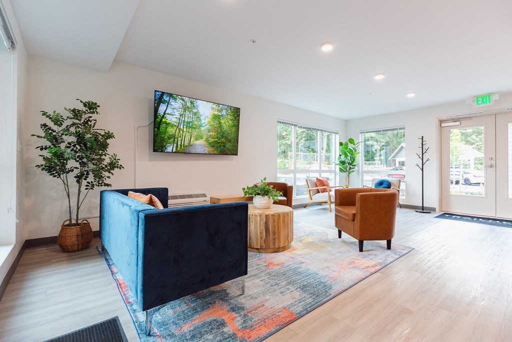 a living room with a blue couch and chairs and a tv on the wall