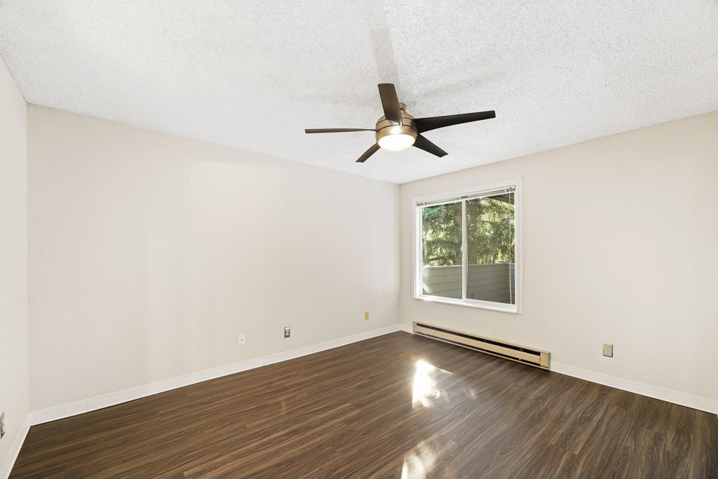 an empty living room with a ceiling fan and a window